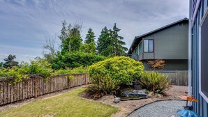 A residential backyard with a wooden fence, a small pond, and a house with a grey exterior. - Quick Hwy Access to Seattle! Mtn-view Apt w/ Yard (Renton)