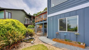 A modern two-story house with a deck, a small garden with ferns, and a gravel pathway. - Quick Hwy Access to Seattle! Mtn-view Apt w/ Yard (Renton)