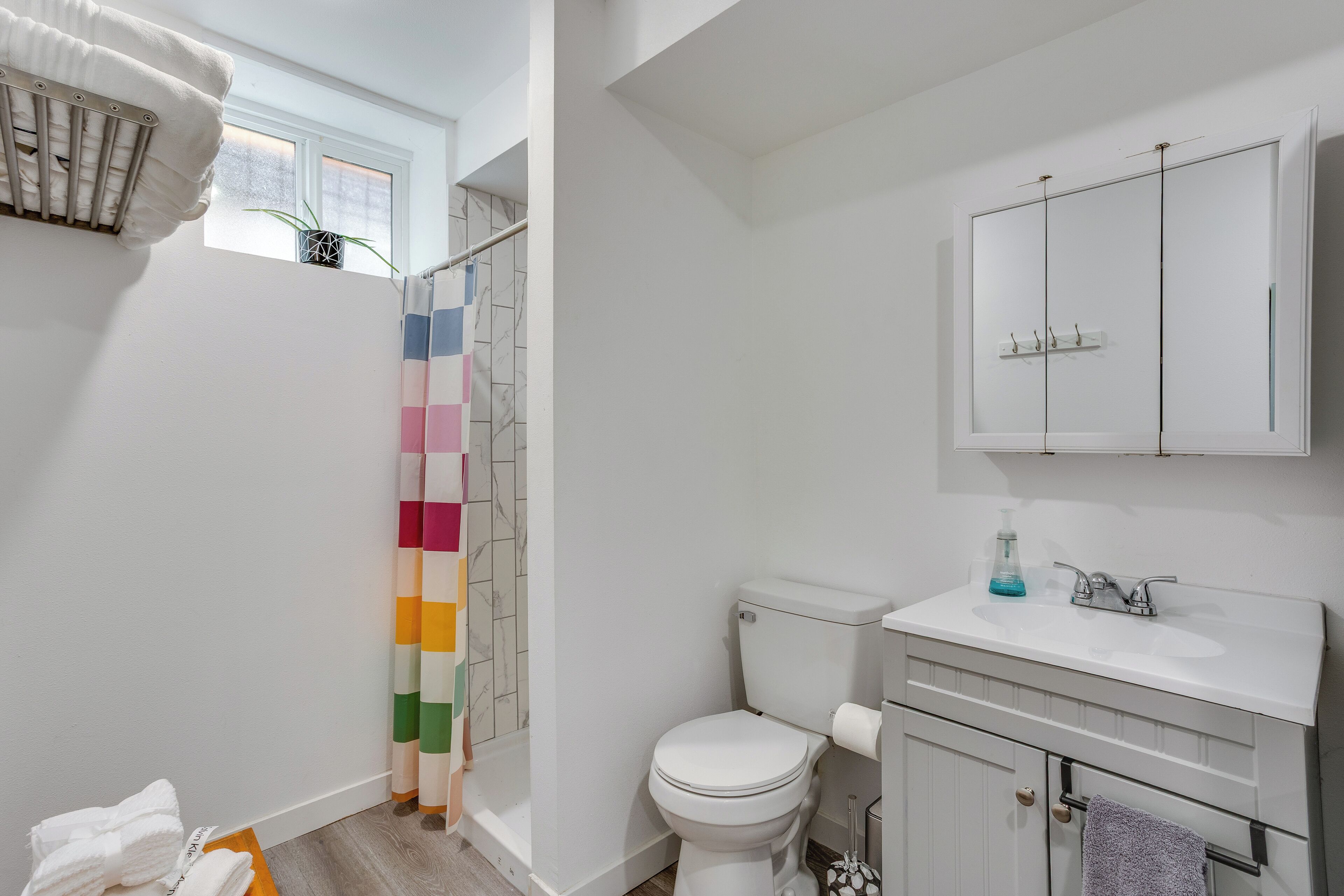 Une salle de bain avec des toilettes blanches, un lavabo blanc, un meuble et un rideau de douche.