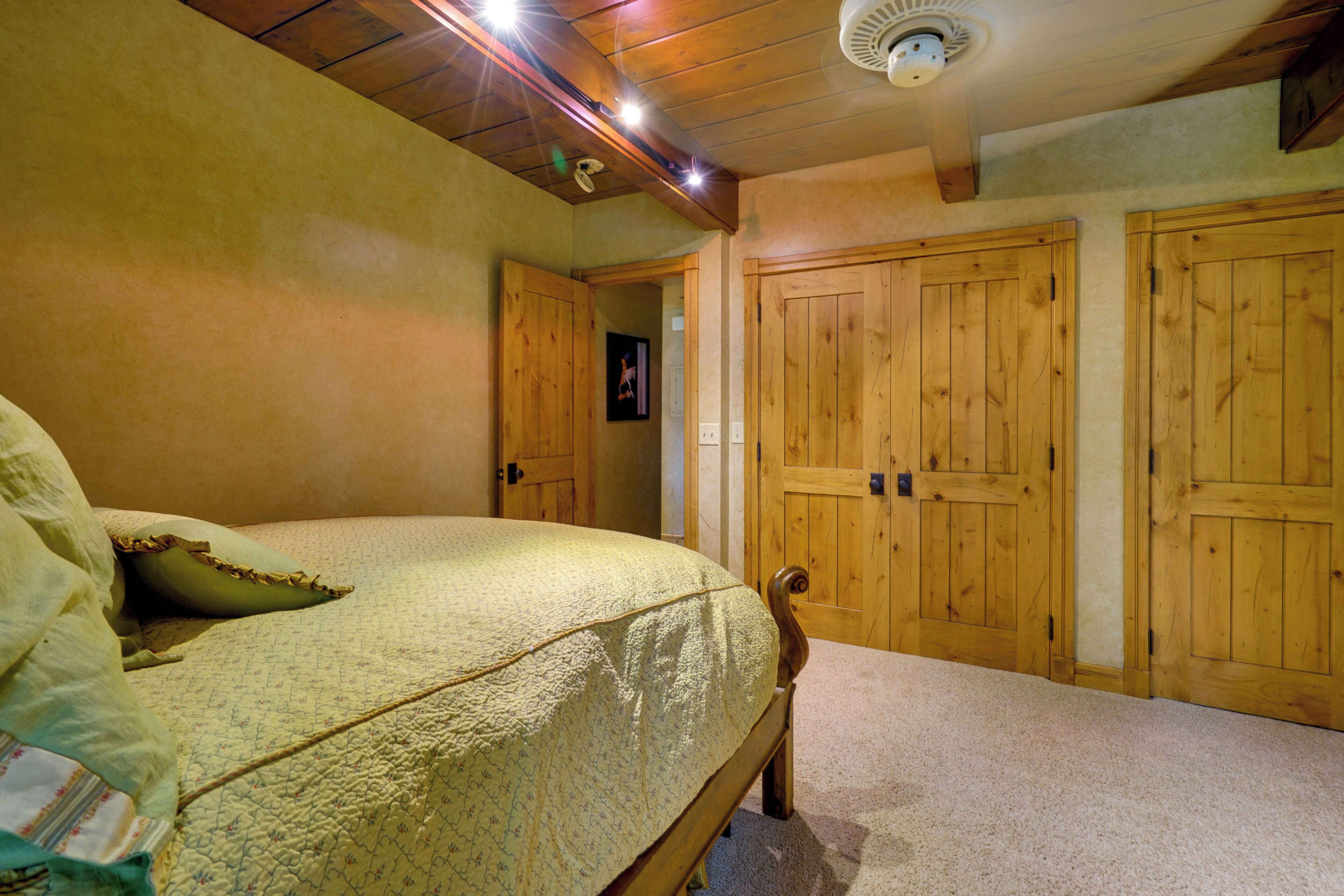 A bedroom with a bed, wooden wardrobe, and a ceiling fan.