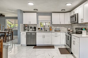 Une cuisine moderne avec des meubles blancs, un lave-vaisselle, un four à micro-ondes et une cuisinière.