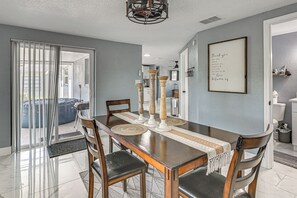 Un coin repas avec une table en bois, des chaises et un message encadré accroché au mur.
