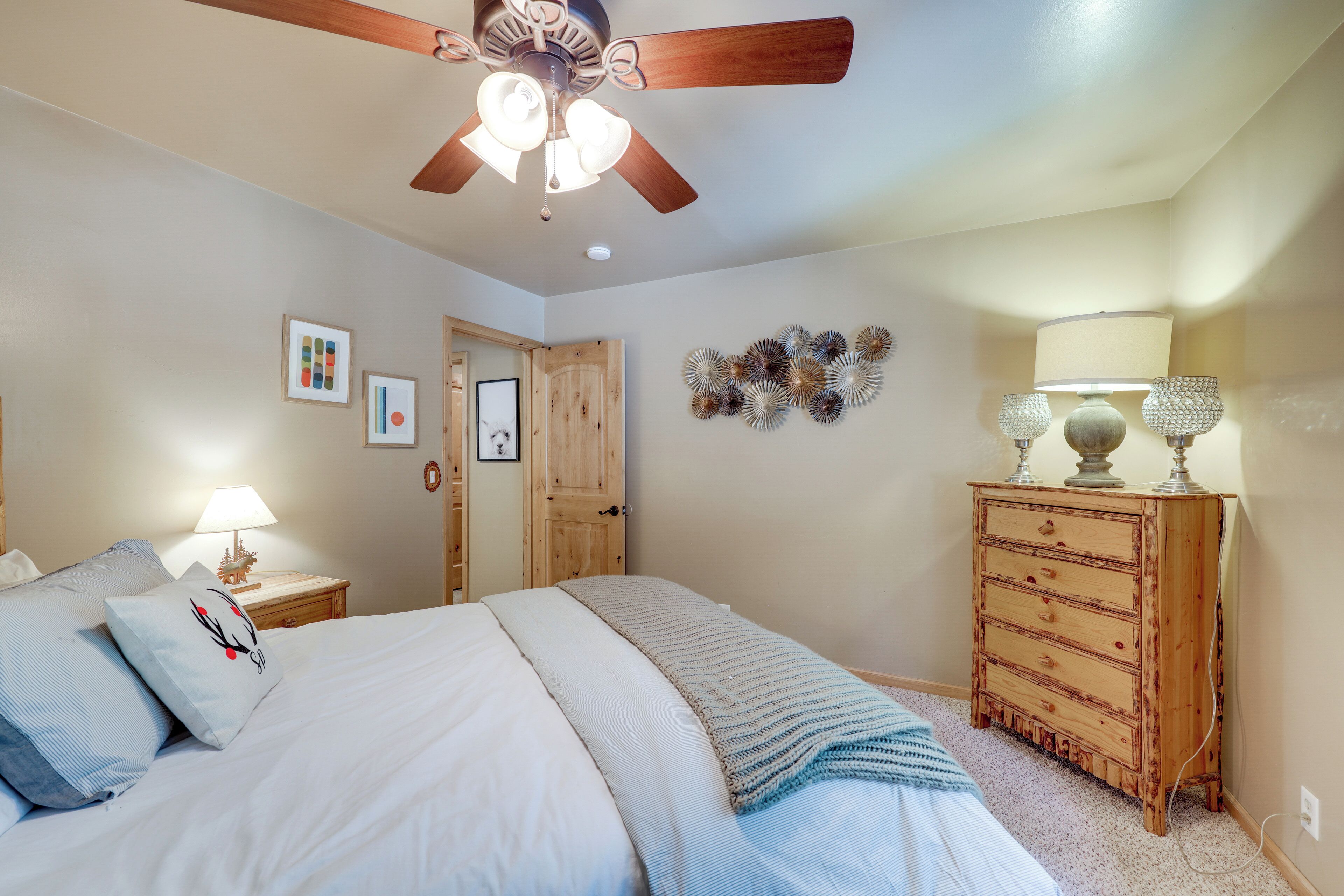 Une chambre à coucher avec un lit, une commode en bois, un ventilateur de plafond et des décorations murales.