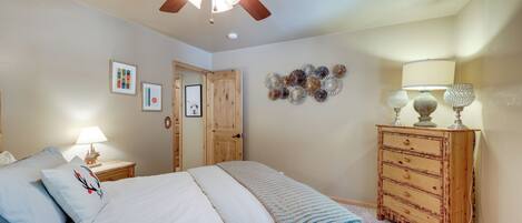 Une chambre à coucher avec un lit, une commode en bois, un ventilateur de plafond et des décorations murales.