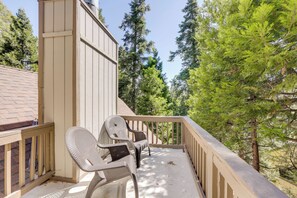 A balcony with two wicker chairs, a wooden railing, and a view of tall trees. - Hot Tub + Forest Views! Lake Arrowhead Cabin (Cedar Glen)
