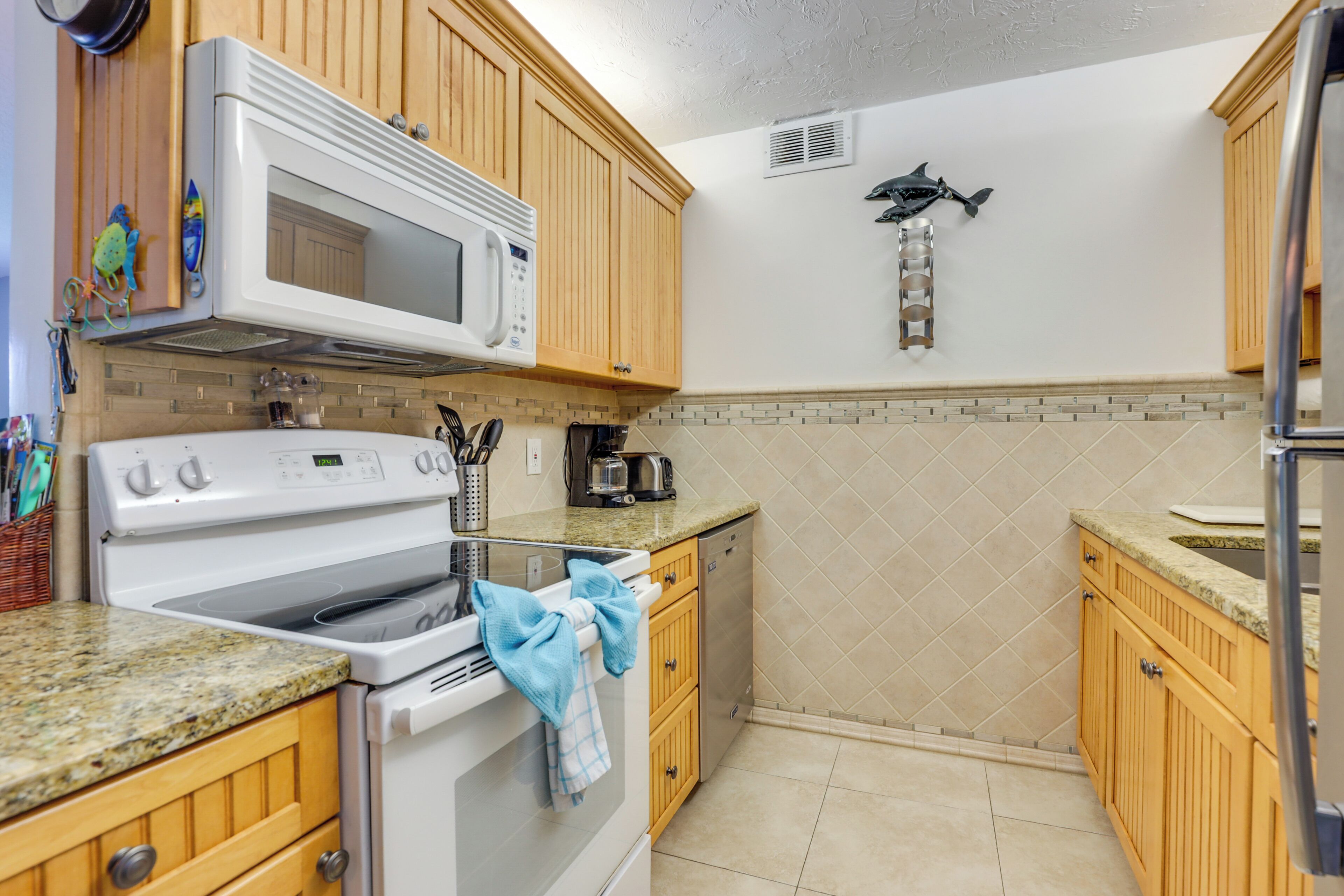 A kitchen with wooden cabinets, a white stove, a microwave, and a fish decoration on the wall.