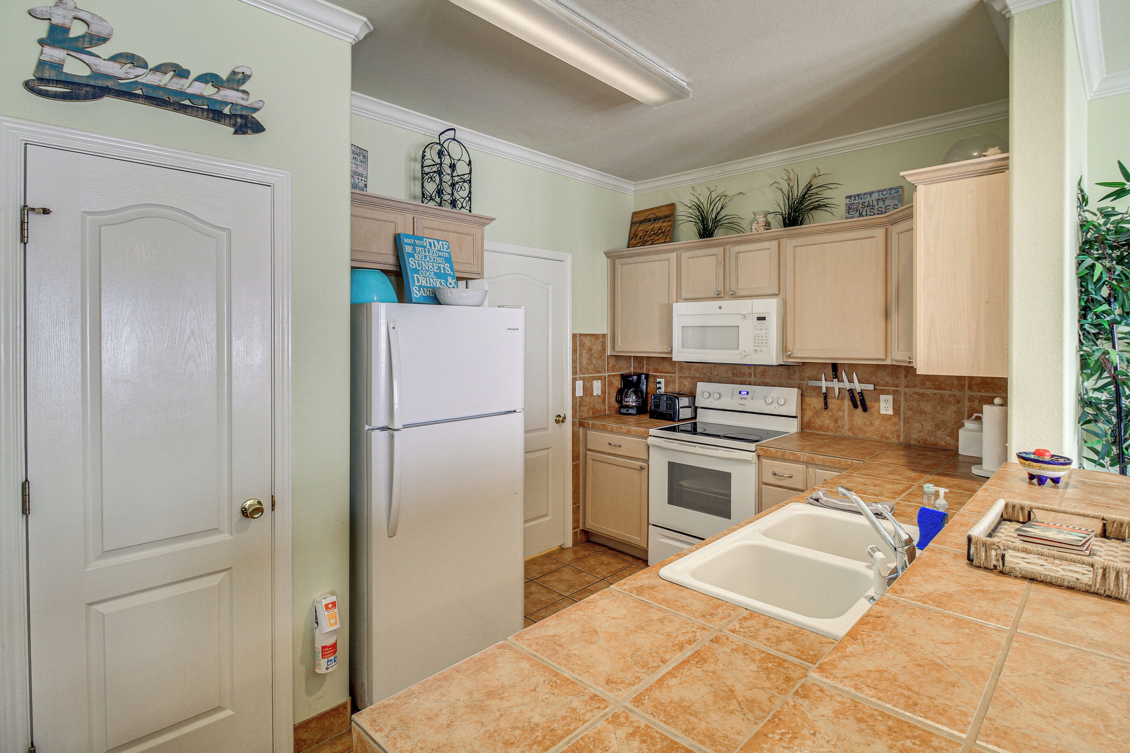 A kitchen with a refrigerator, microwave, stove, and sink.