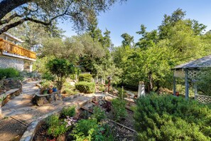 Um jardim com caminho de pedra, deck de madeira e um gazebo.