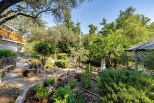Un jardín con un sendero de piedra, terraza de madera y un pabellón.