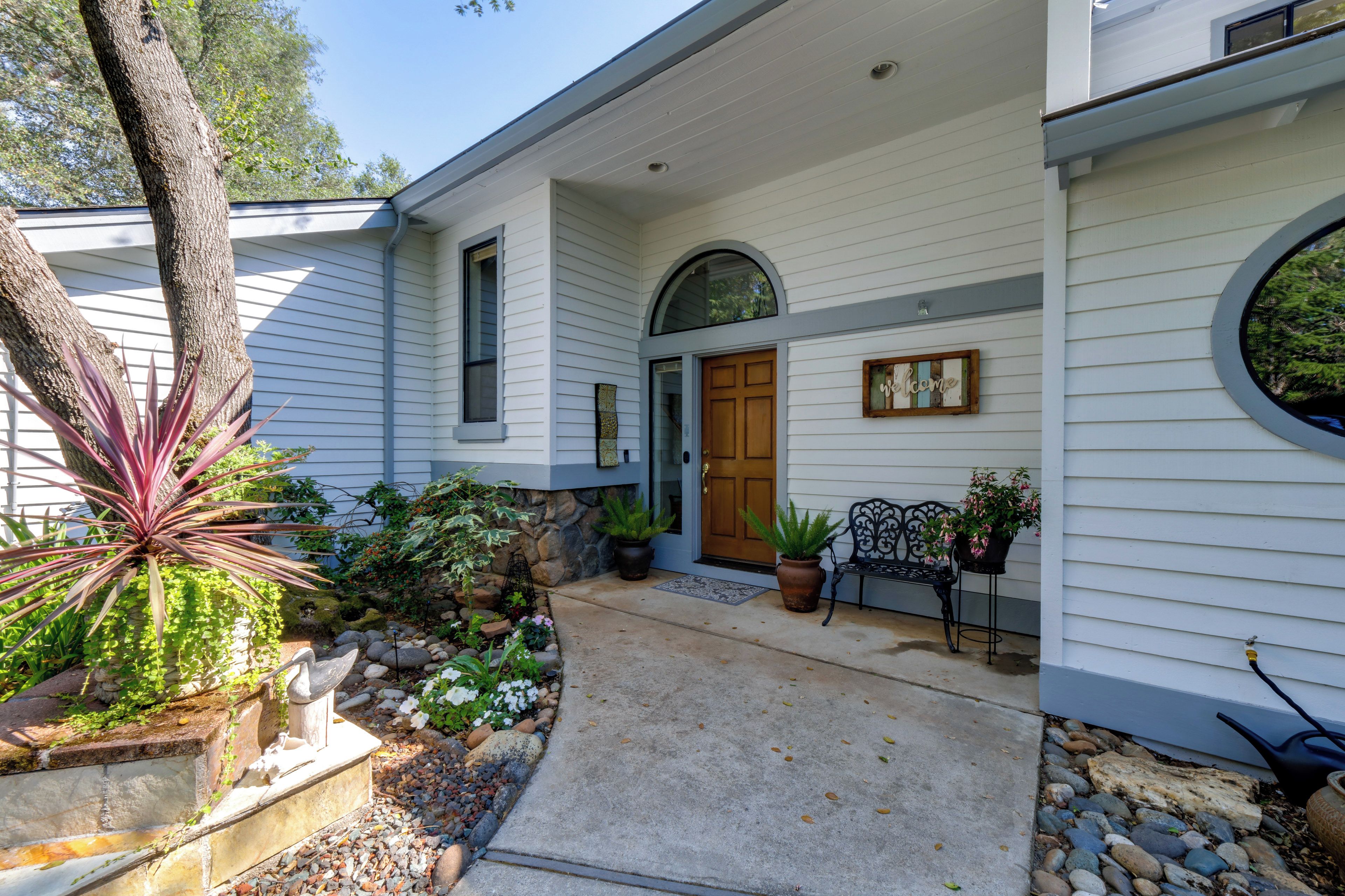 A house with a front porch, a wooden door, and potted plants.