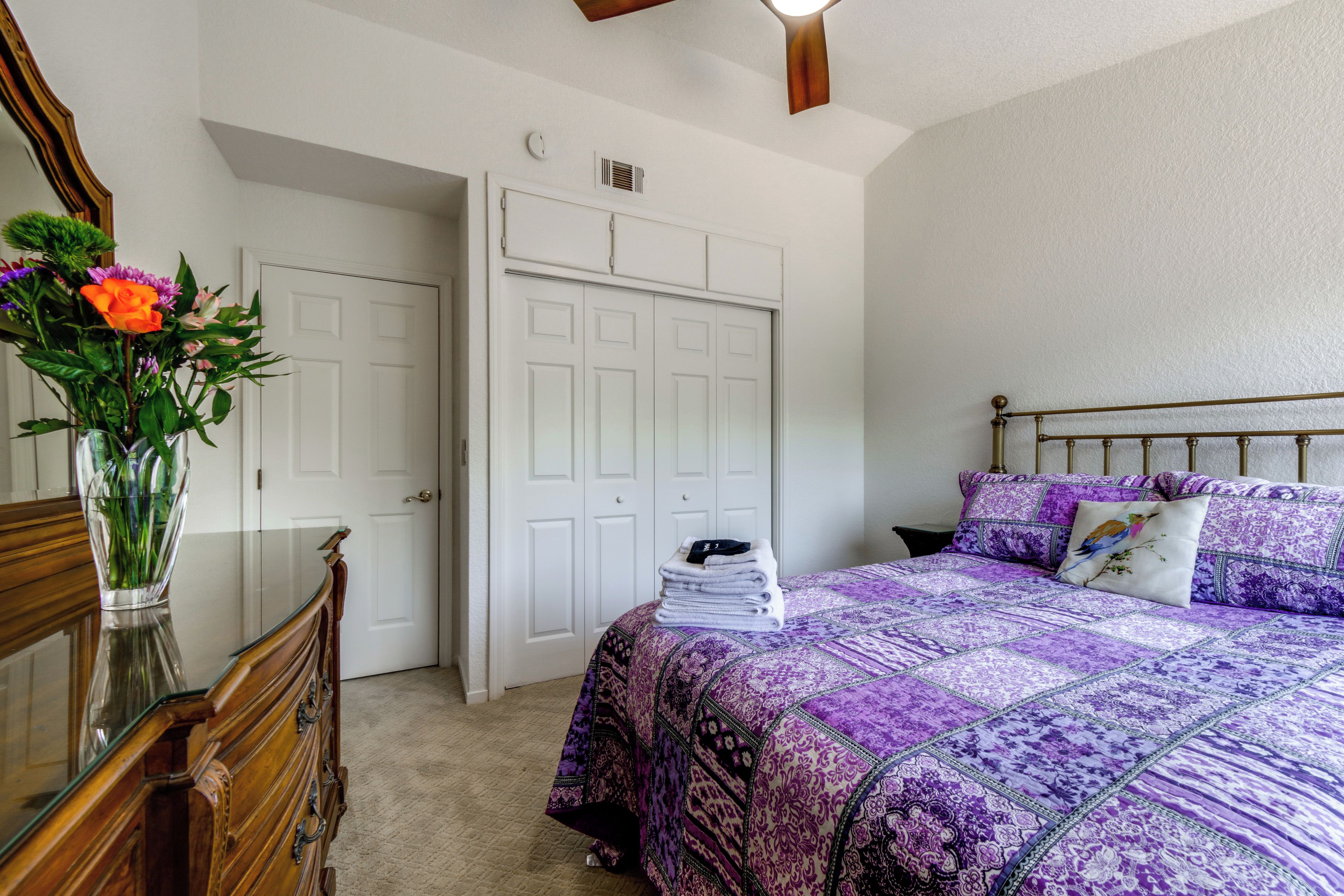 Ein Schlafzimmer mit Bett, Kommode und einem Blumenstrauß.