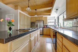 Una cocina moderna con armarios de madera, un refrigerador de acero inoxidable y una encimera de granito.
