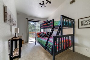 A bunk bed with colorful bedding, a desk with a lamp, and a ceiling fan. - Creekside Hideaway in Auburn! 4BR Home w/ Pool (Auburn)