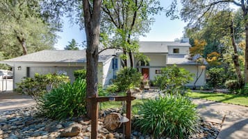 A house with a garage, a well-maintained garden with various plants, and a wooden swing set.