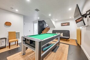 A modern living room with a pool table, a sofa, a chair, and a staircase leading to another level. - Spacious Kanab Basecamp Game Rm, Patio, Fire Pit (Kanab)