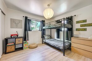 Dormitorio con literas, una ventana, una estantería y un escritorio.