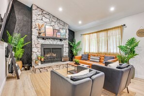 Una sala moderna con chimenea de piedra, sofás de cuero y plantas en macetas.