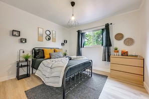 A modern bedroom with a bed, bedside tables, a dresser, and a window with curtains. - Spacious Kanab Basecamp Game Rm, Patio, Fire Pit (Kanab)