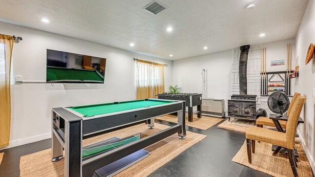 A pool table with a green felt surface, a fireplace, and a fan in a room with white walls and a ceiling with recessed lighting. - Spacious Kanab Basecamp Game Rm, Patio, Fire Pit (Kanab)