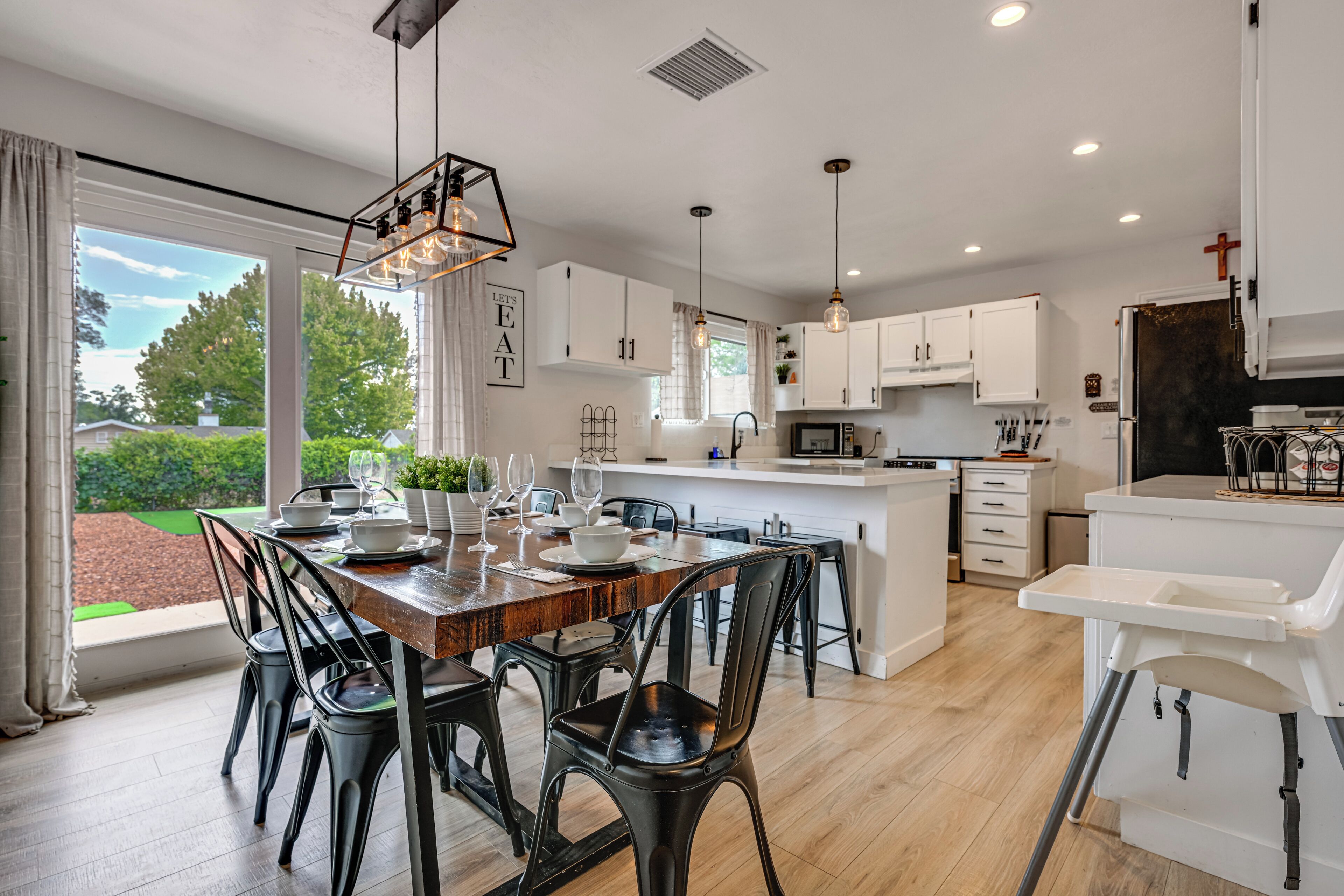A modern kitchen with white cabinets, a wooden dining table, and black chairs.