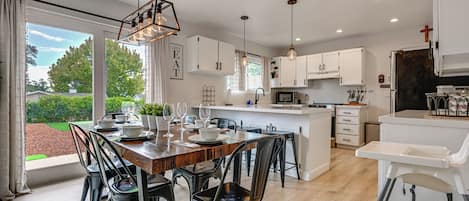 A modern kitchen with white cabinets, a wooden dining table, and black chairs.