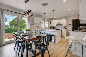 Una cocina moderna con armarios blancos, una mesa de comedor de madera y sillas negras.