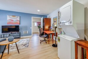 A living room with a TV, wooden furniture, a dining table, and a washing machine. - Work-friendly Seattle Retreat By Parks + Hospitals (Seattle)