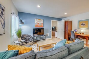 A living room with a TV, sofa, coffee table, and a dining area with a table and chairs. - Work-friendly Seattle Retreat By Parks + Hospitals (Seattle)