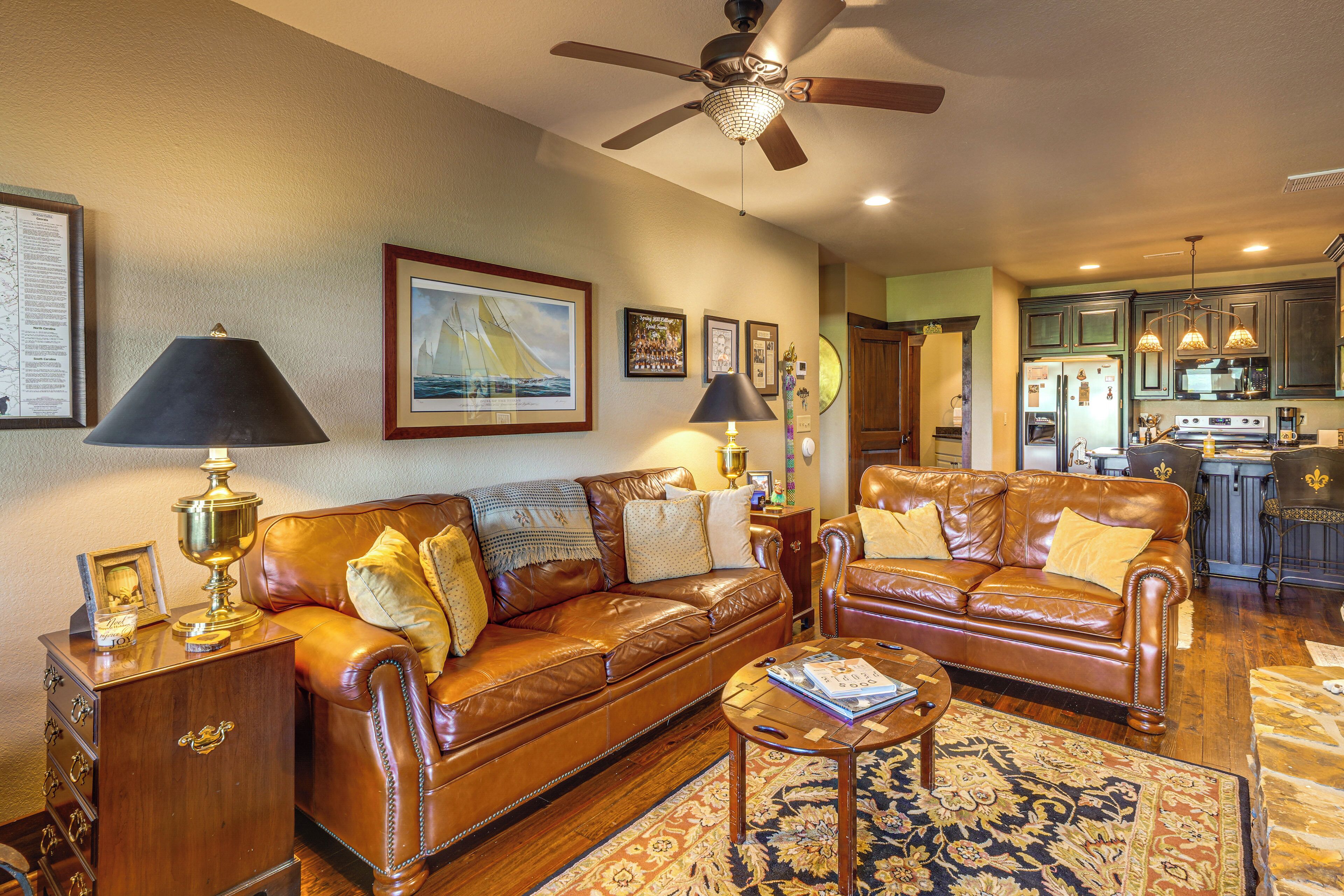 A living room with a brown leather sofa, a coffee table, and a ceiling fan.