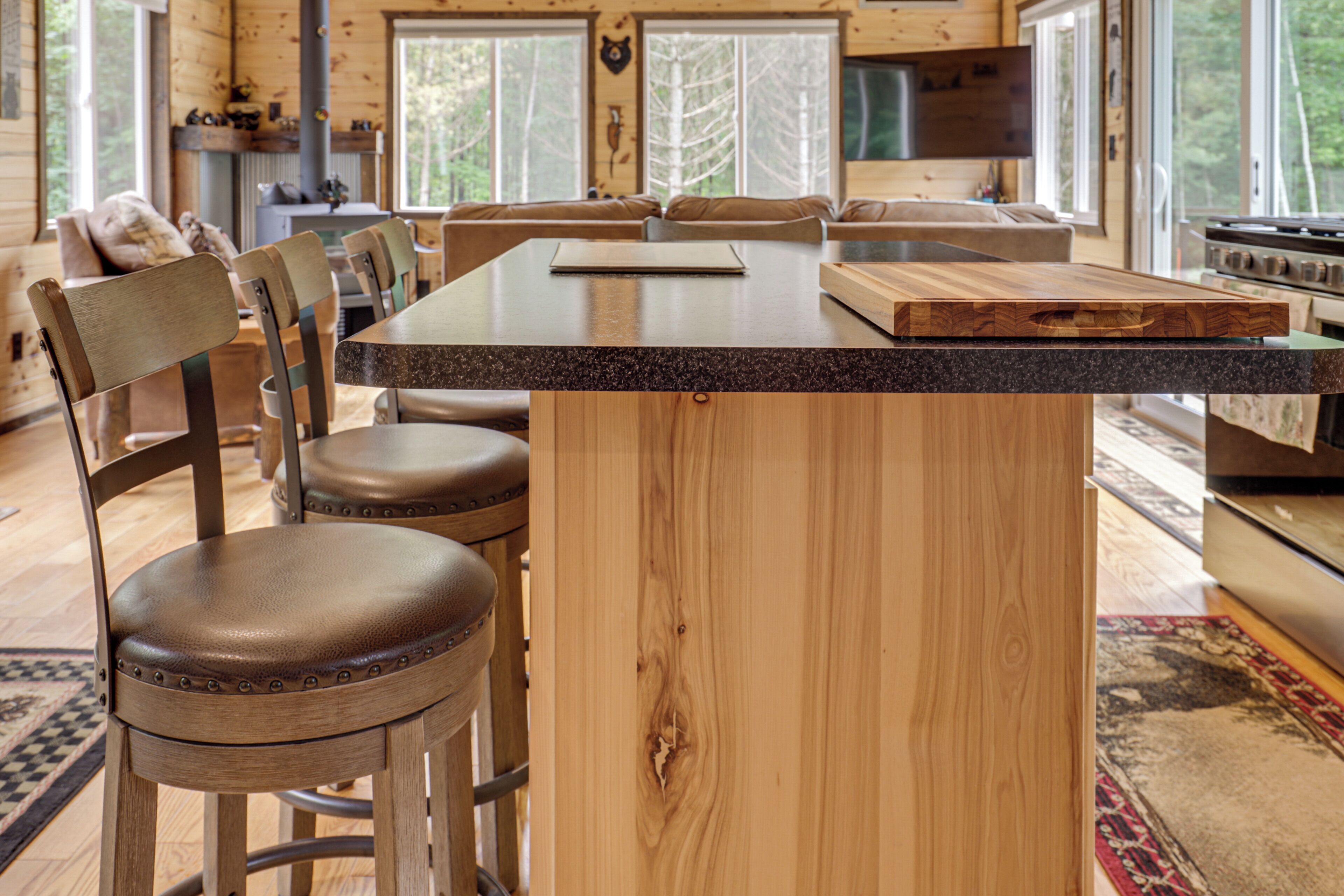 A wooden interior with a kitchen island, bar stools, and a fireplace.