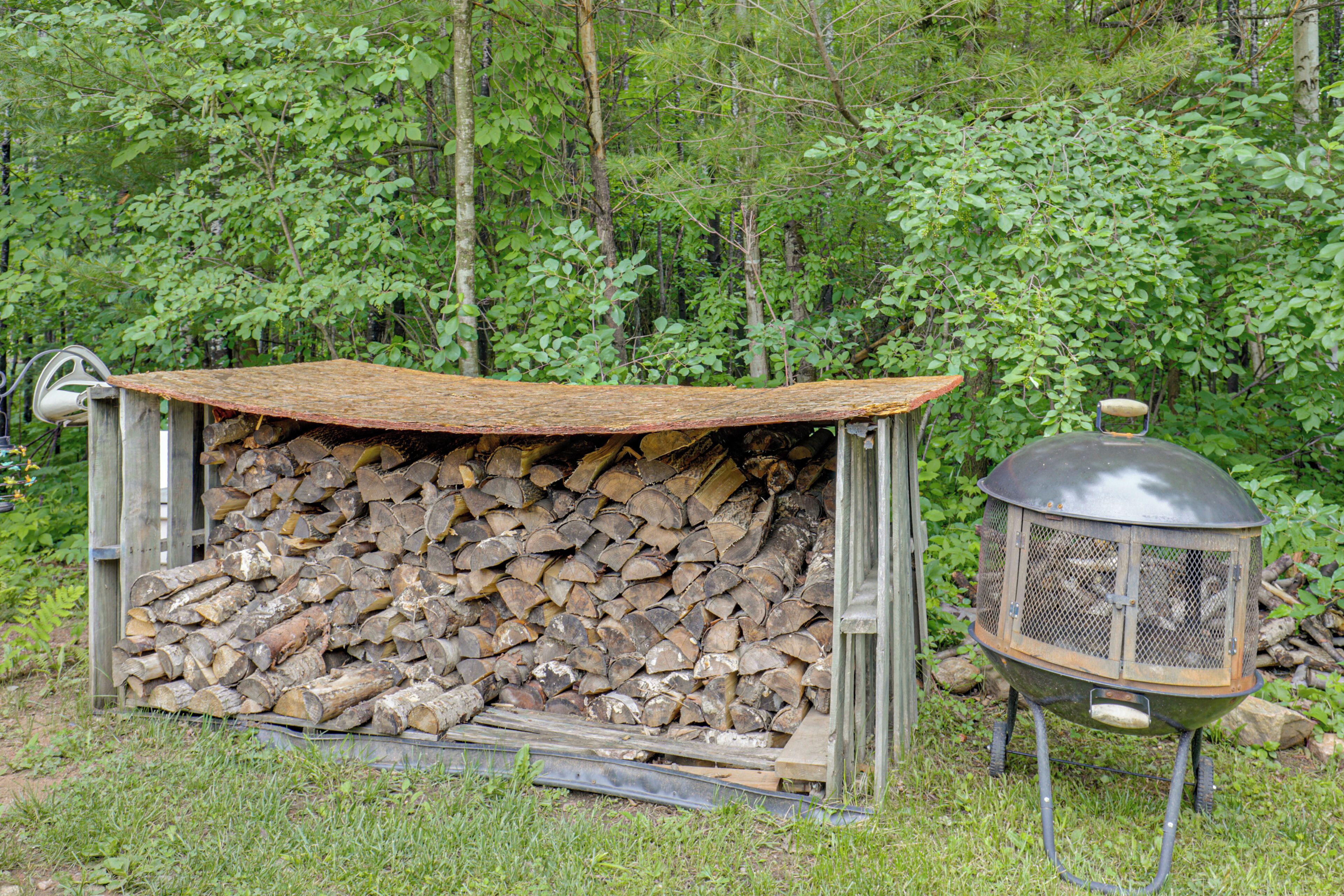 Entorno rústico al aire libre con una estructura metálica que contiene un montón de leña y una parrilla de metal.