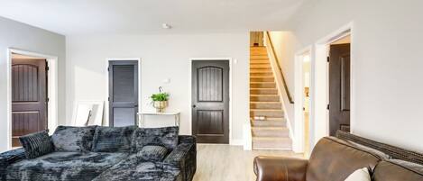 A living room with a dark patterned sofa, a brown leather sofa, and a staircase leading to another level.