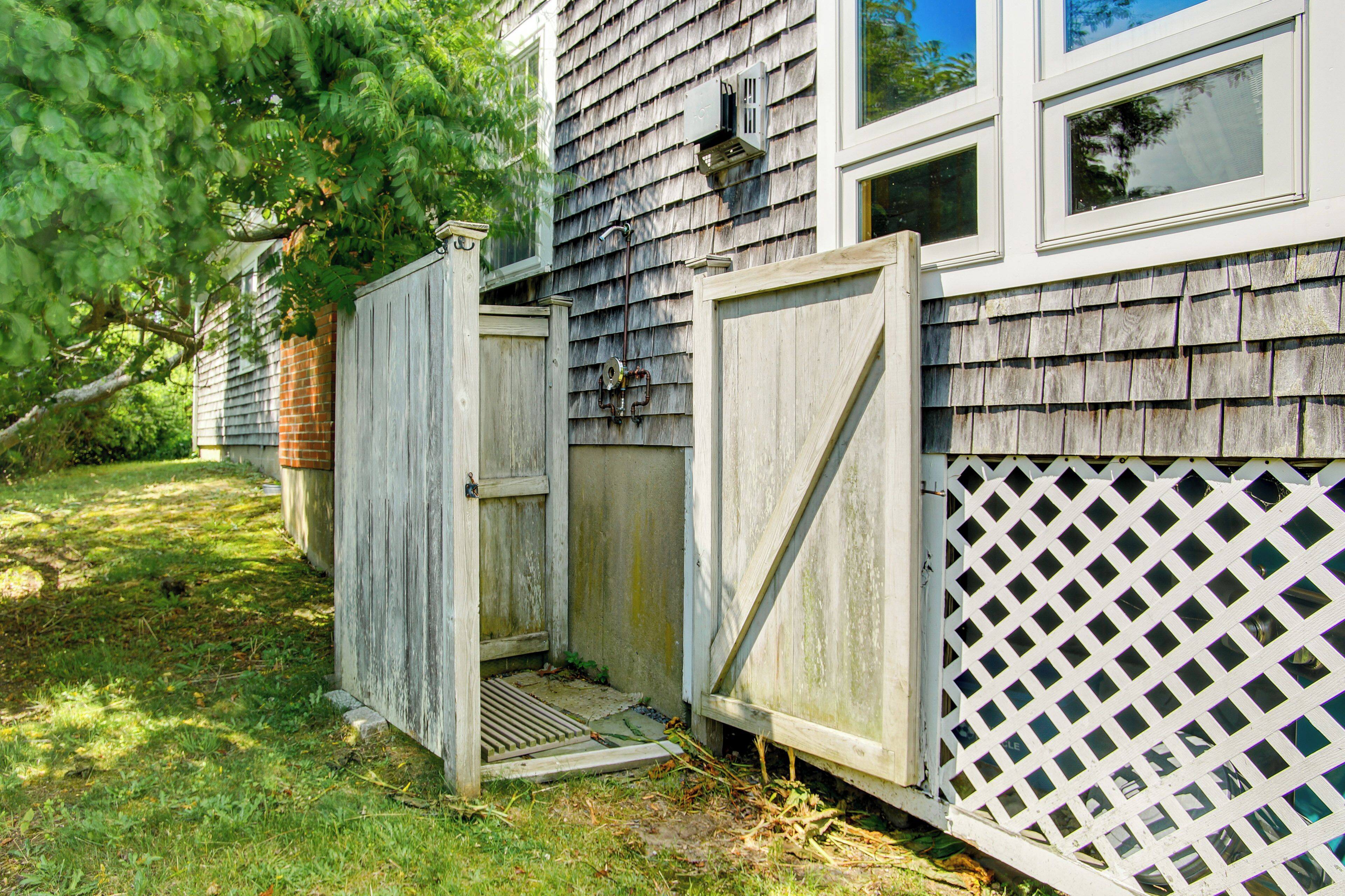 A wooden fence with a gate, a wooden deck, and a house with siding and windows.