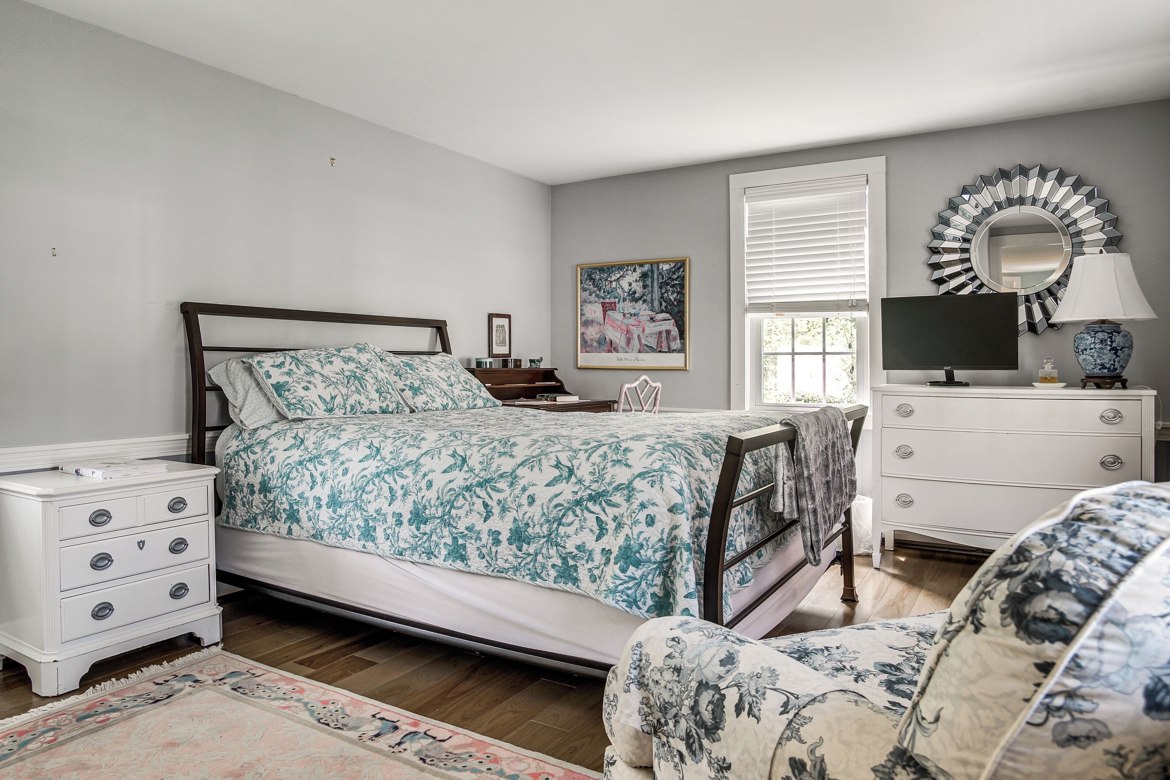Une chambre à coucher comprenant un lit, une table de chevet, une commode, une chaise et un miroir.