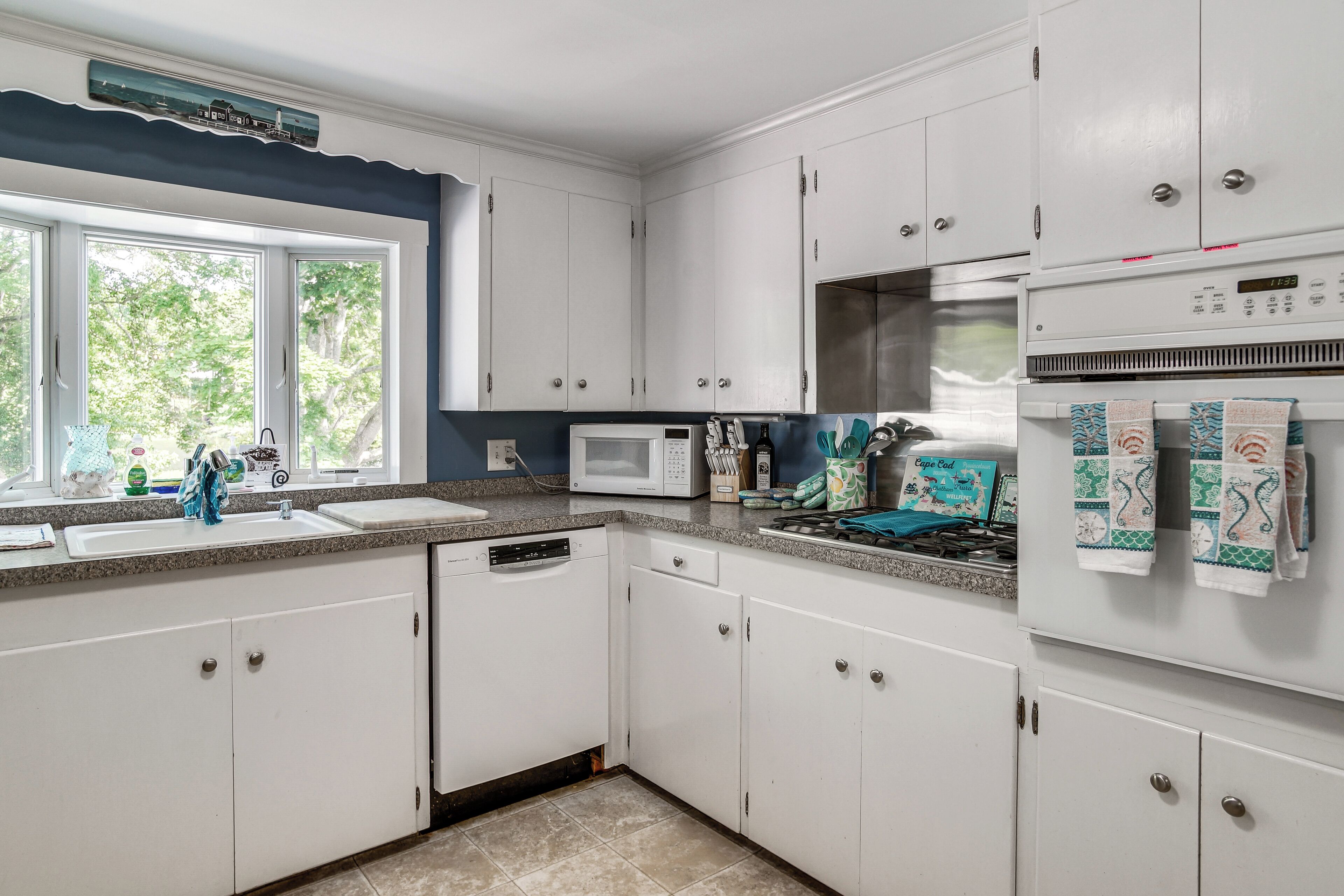 A kitchen with white cabinets, a microwave, a stove, and a dishwasher.