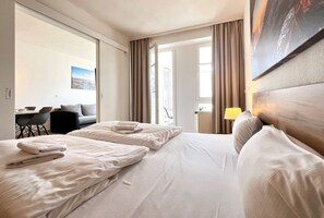 Une chambre d’hôtel avec deux lits, un bureau, une chaise et une vue sur l’extérieur.