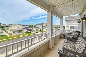 A covered porch with a view of a residential street, a wicker sofa, and a table. - Walk to Brigantine Beach! Family Townhome w/ Views (Brigantine)