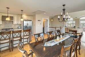A spacious kitchen with wooden cabinets, a stainless steel refrigerator, and a dining area with a large wooden table and chairs. - Walk to Brigantine Beach! Family Townhome w/ Views (Brigantine)