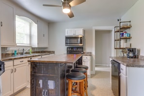 A kitchen with a central island, bar stools, a ceiling fan, and built-in appliances. - 2 Mi to Spring River Fishing! Quiet Escape w/ Yard (Carthage)