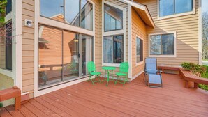 A deck with a table and chairs, large windows, and a bench.