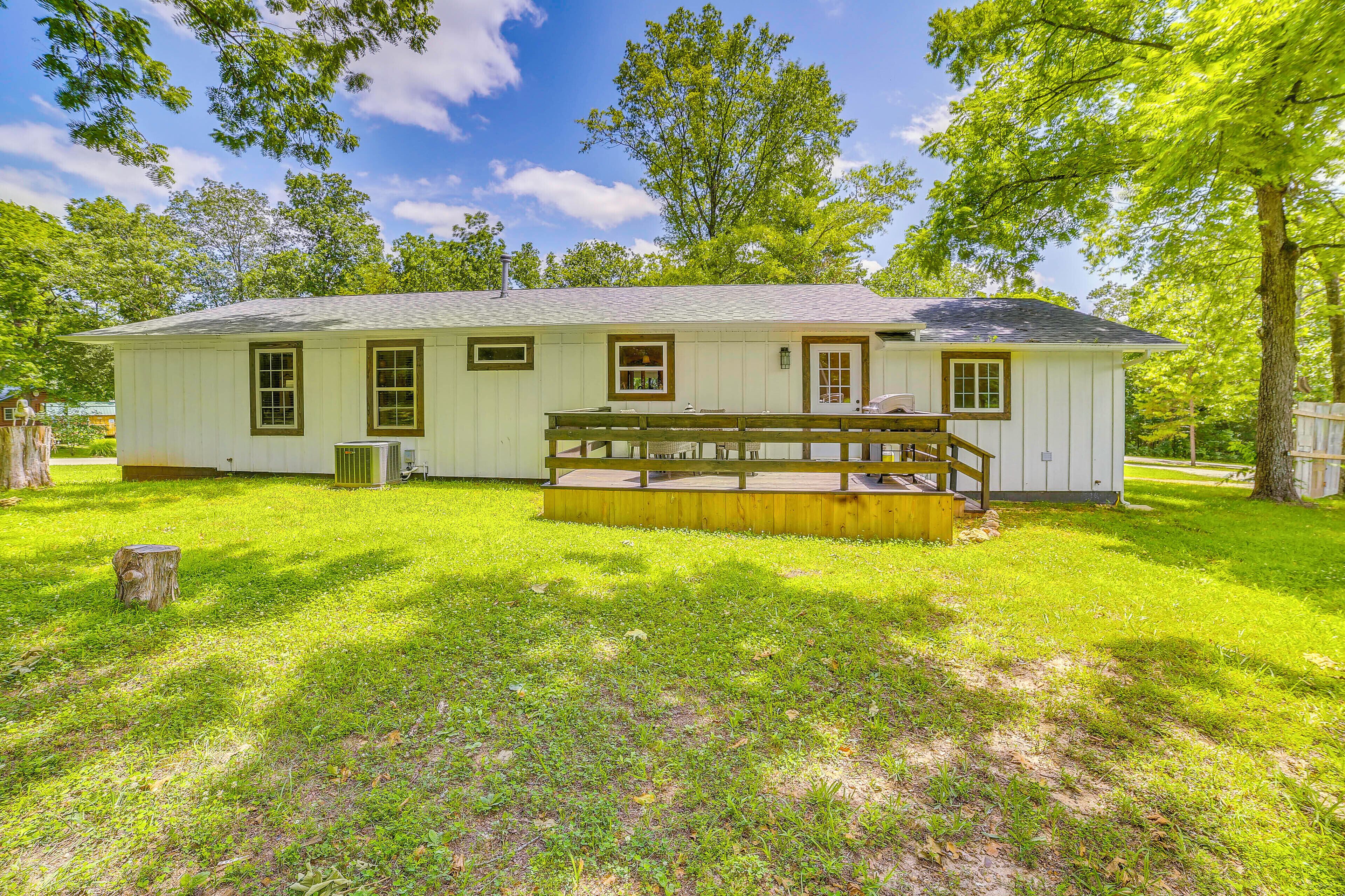 A single-story white building with a porch, surrounded by a well-maintained lawn and trees.