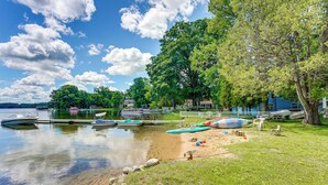A lakeside scene with boats docked, a sandy beach, and a white fence. - Pet-friendly Bass Lake Cabin: Beach & Boat Dock (Irons)