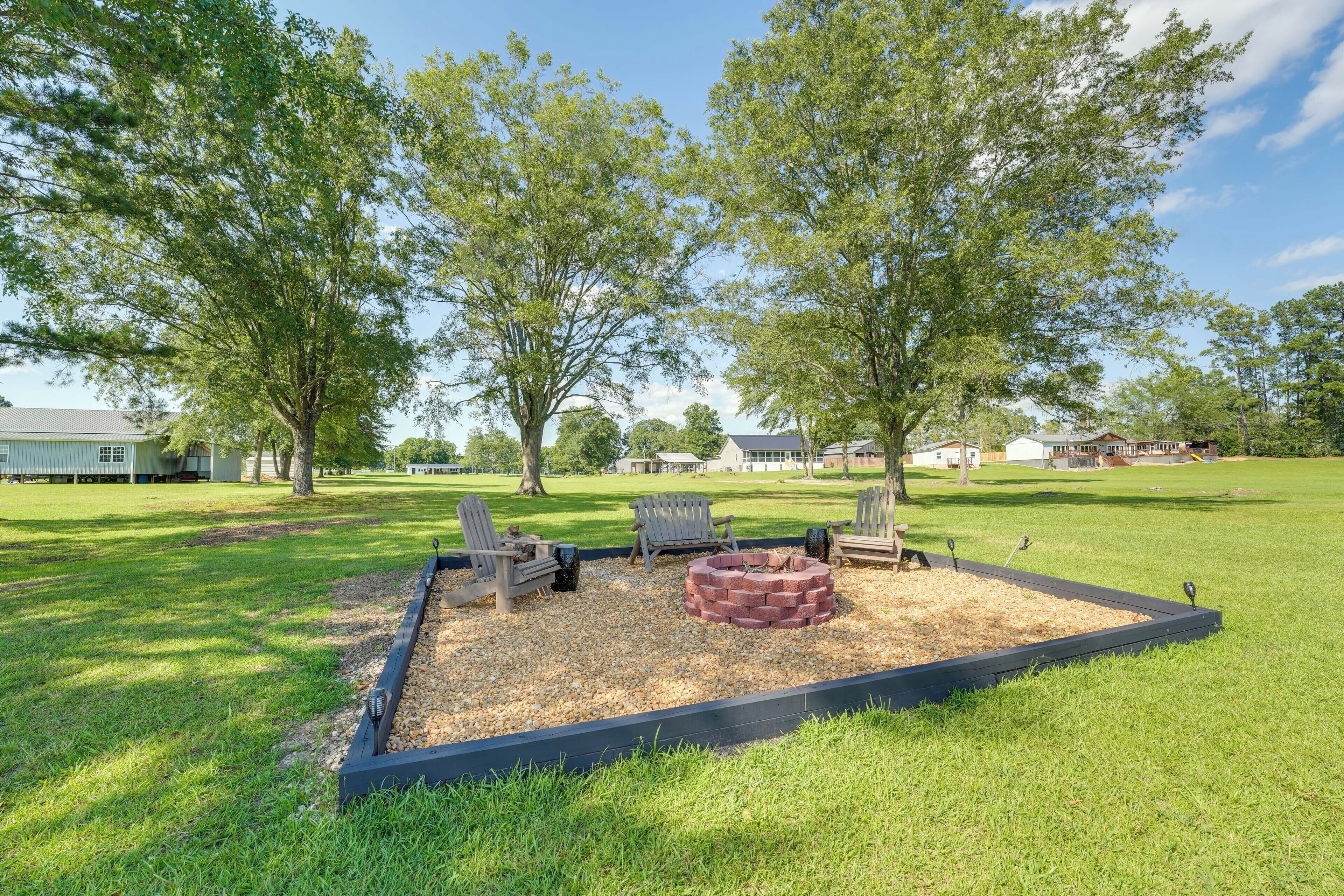 A landscaped outdoor area with a fire pit, seating, and trees.