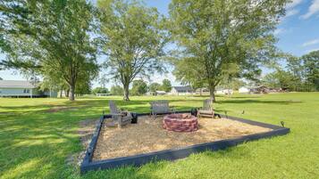 A landscaped outdoor area with a fire pit, seating, and trees.