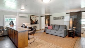 A spacious living area with a wooden bar, a gray sofa, and a large window. - 'cast a Line Cabin' w/ Dock on Weiss Lake (Centre)