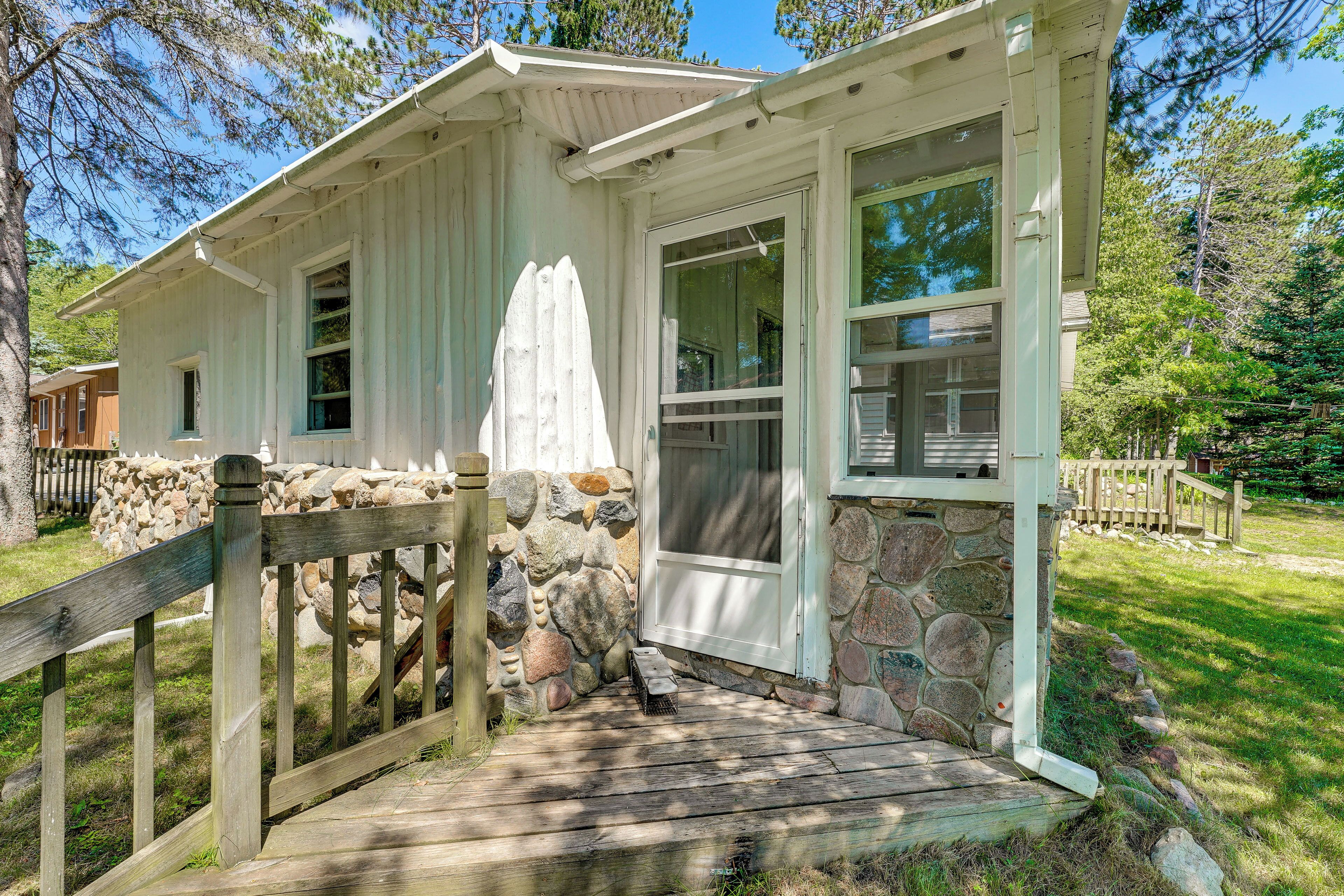 A house with a stone foundation, a wooden porch, and a screened porch area.