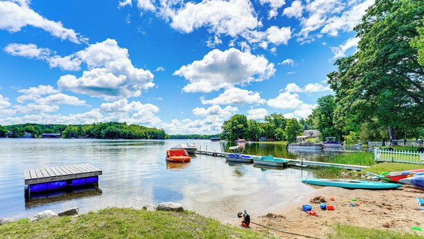 A lakeside dock with boats, a wooden pier, and a sandy beach. - Swim, Boat, Fish On-site: Quaint Bass Lake Cabin! (Irons)