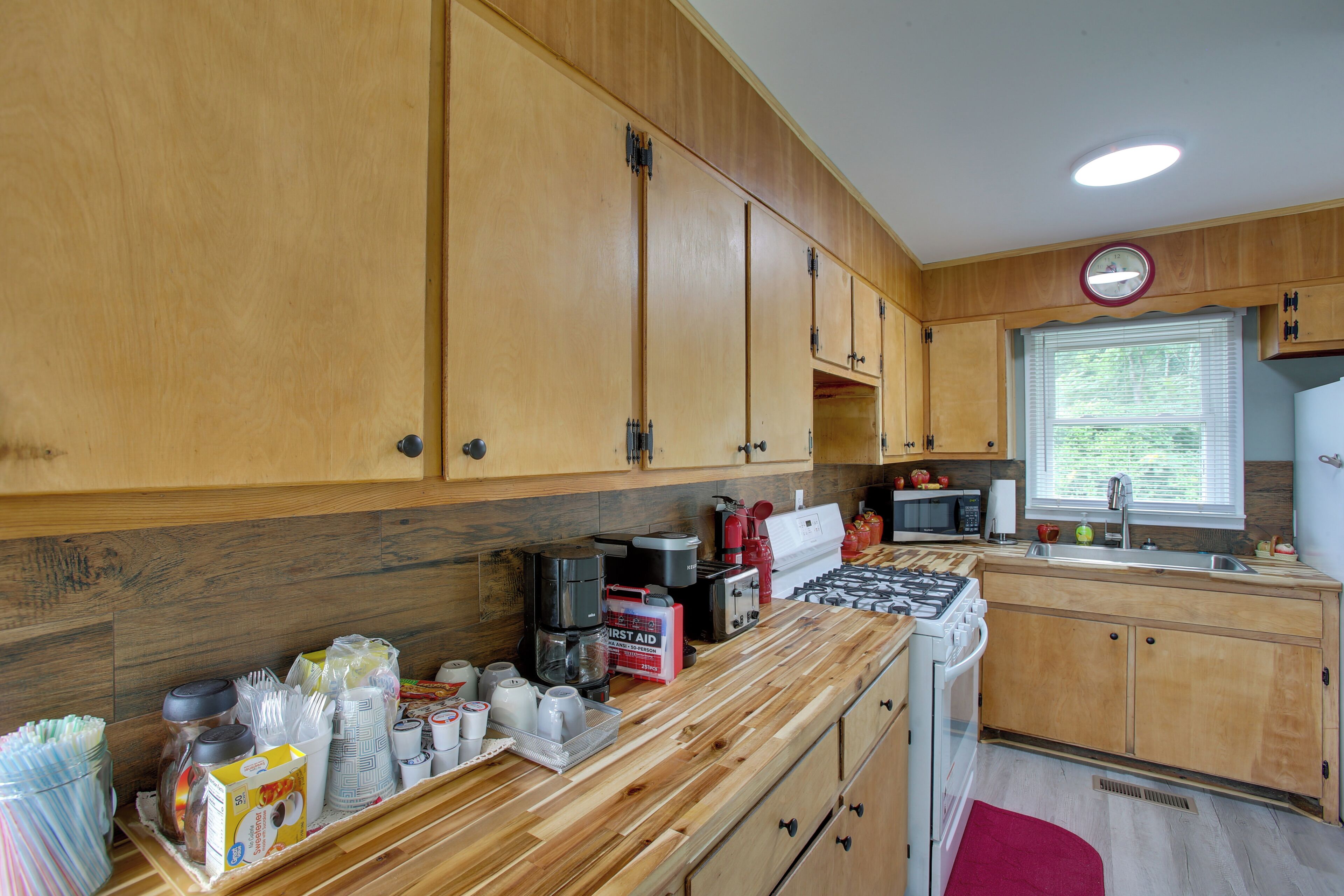 A kitchen with wooden cabinets, a gas stove, a microwave, and a sink.