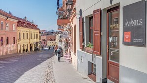 A cobblestone street lined with buildings, including a restaurant named 'AMANDUS' with outdoor seating. - New! Luxury Old town apartment (Vilnius)