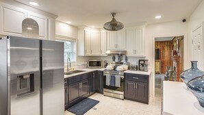 A modern kitchen with stainless steel appliances, white cabinetry, and a central island.